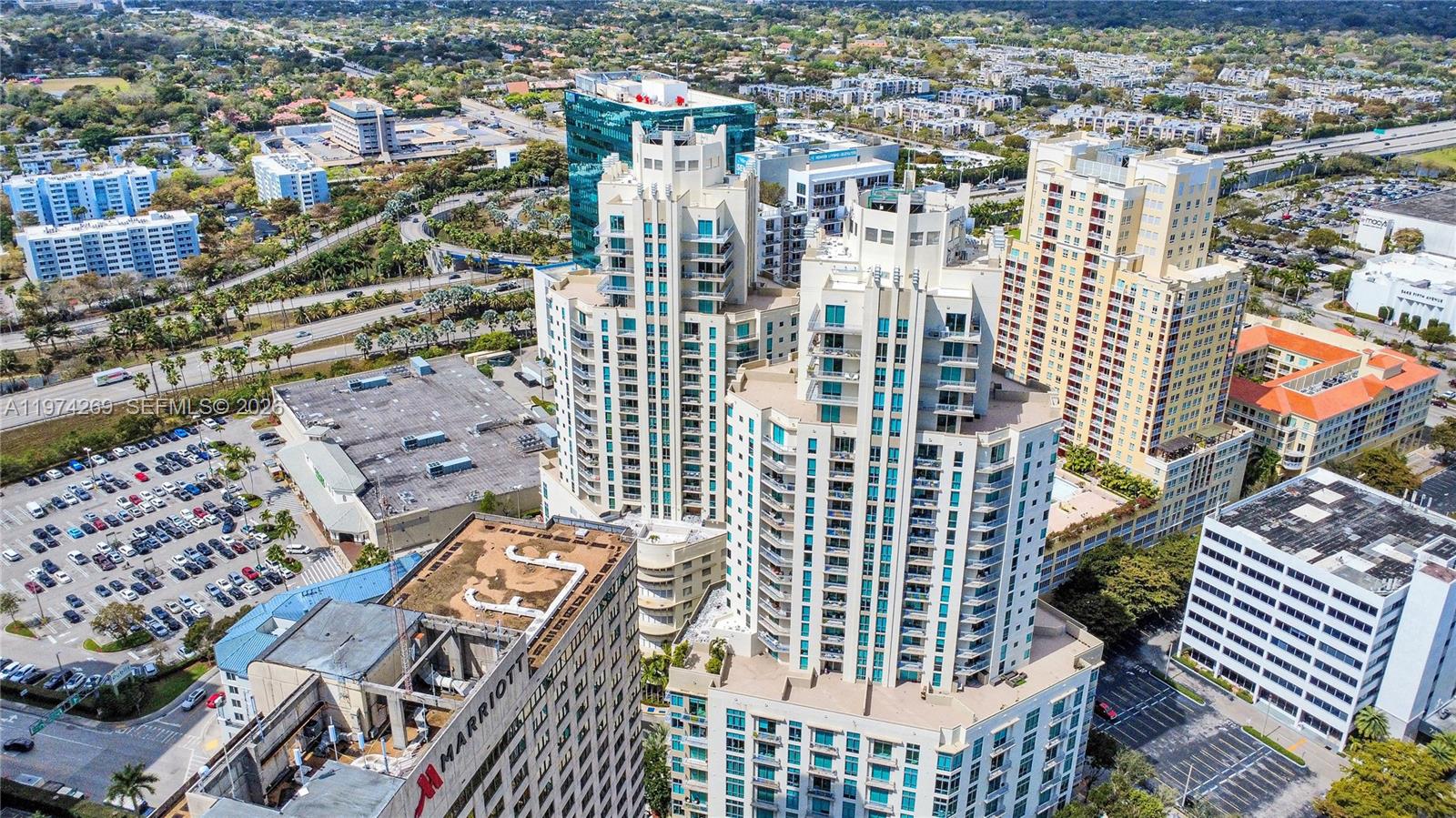 An aerial view shows several high-rise apartment buildings and a hotel near a parking lot — 9066 SW 73rd Ct # 203, Miami FL 33156, MIAMI, FL