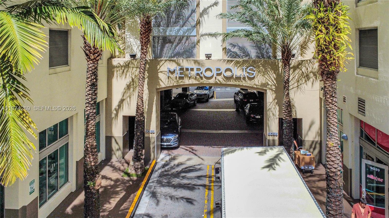 An exterior view shows the entrance to a building labeled Metropolis with palm trees — 9066 SW 73rd Ct # 203, Miami FL 33156, MIAMI, FL