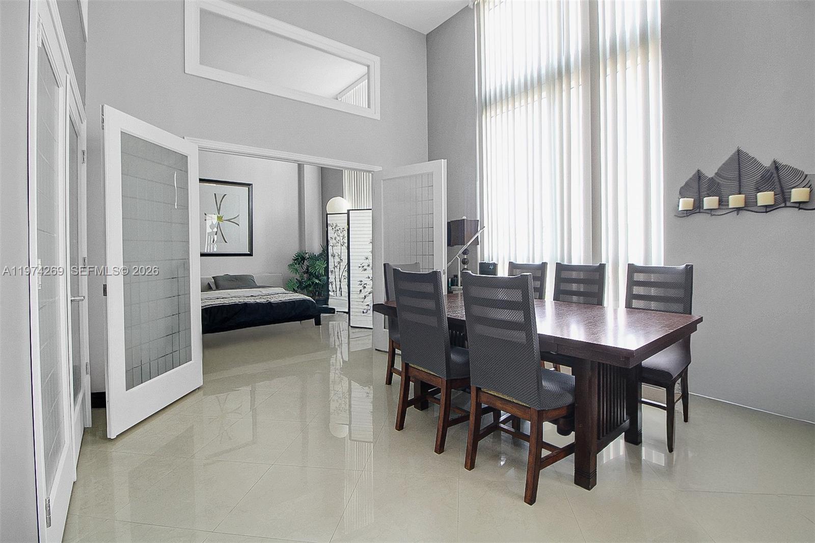 A dining room with a wooden table and chairs sits adjacent to a bedroom — 9066 SW 73rd Ct # 203, Miami FL 33156, MIAMI, FL