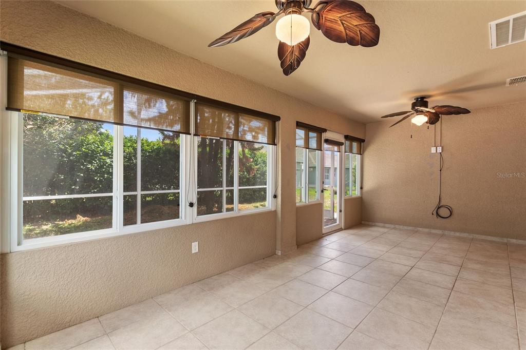 A sunroom with tile flooring, two ceiling fans, and large windows with brown shades — 4130 BEDFORD AVENUE, WINTER HAVEN, FL