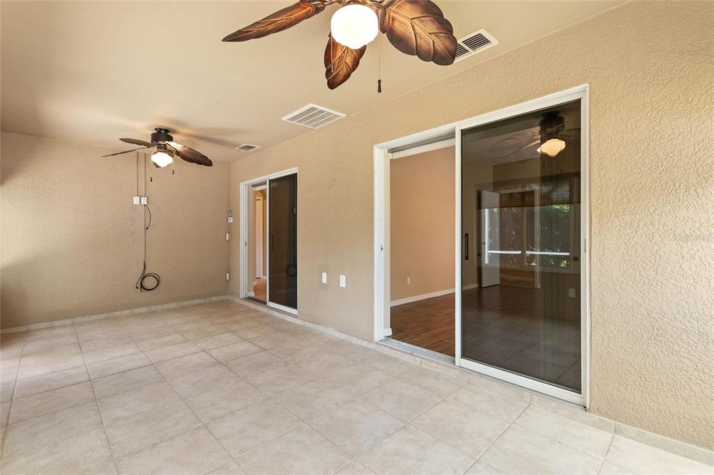 A covered patio with tiled flooring, two ceiling fans, and two sliding glass doors — 4130 BEDFORD AVENUE, WINTER HAVEN, FL