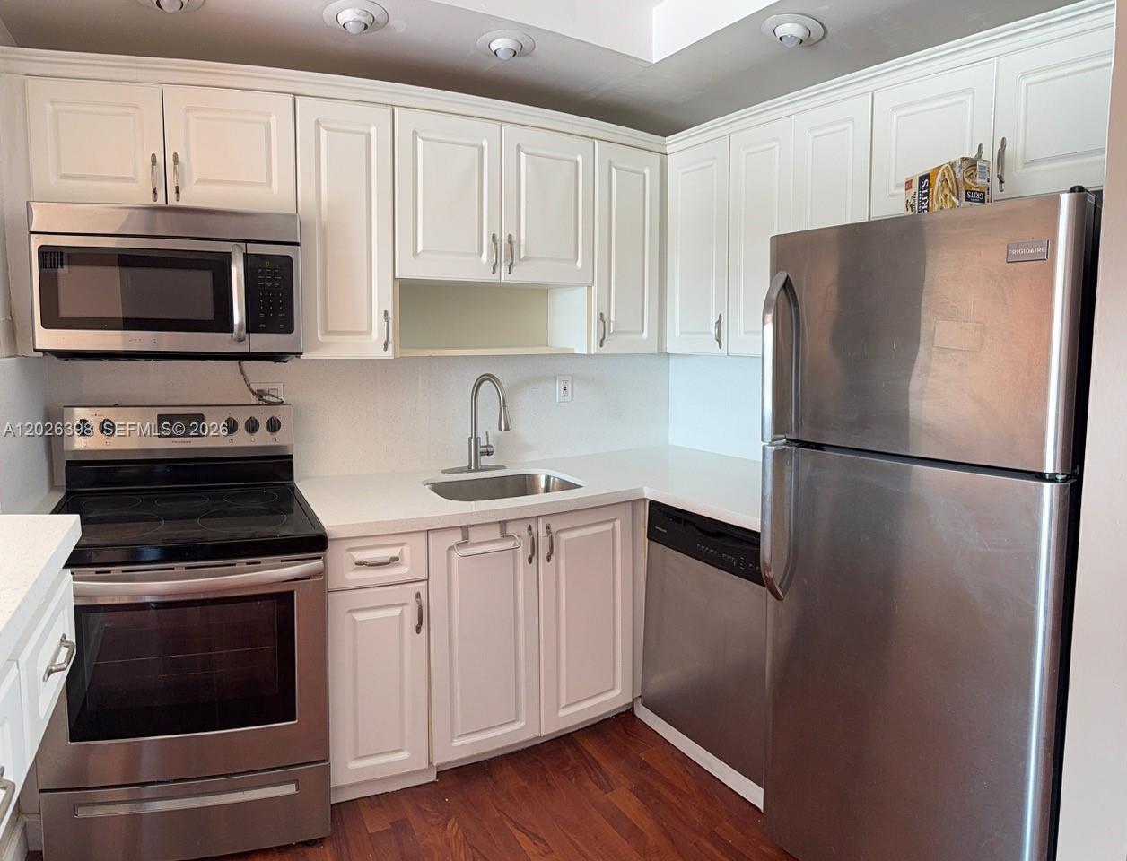 A kitchen features white cabinets, stainless steel appliances, a sink, and dark wood flooring — 8950 NE 8th Ave # 405, Miami FL 33138, MIAMI, FL