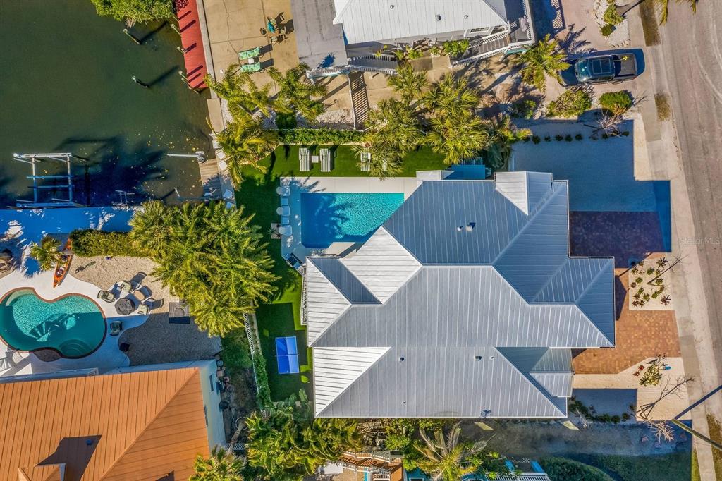 An aerial view shows a house with a metal roof, swimming pool, and waterfront dock — 505 S BAY BOULEVARD, ANNA MARIA, FL