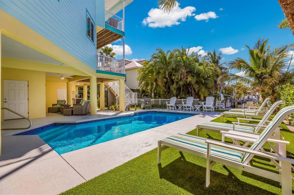 A swimming pool sits beside a multi-story house with a covered patio and lounge chairs — 505 S BAY BOULEVARD, ANNA MARIA, FL
