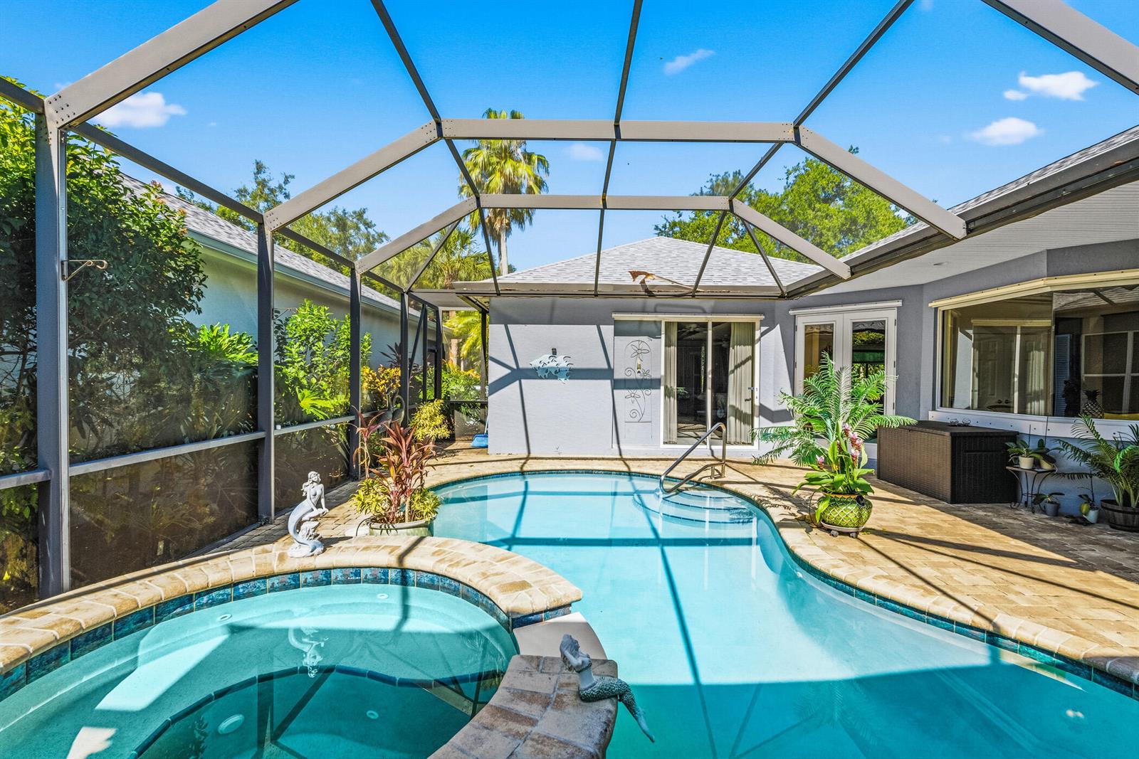 A screened-in patio features a swimming pool, a hot tub, and a paved deck — 228 Oak Hammock Circle SW, Vero Beach FL 32962, VERO BEACH, FL