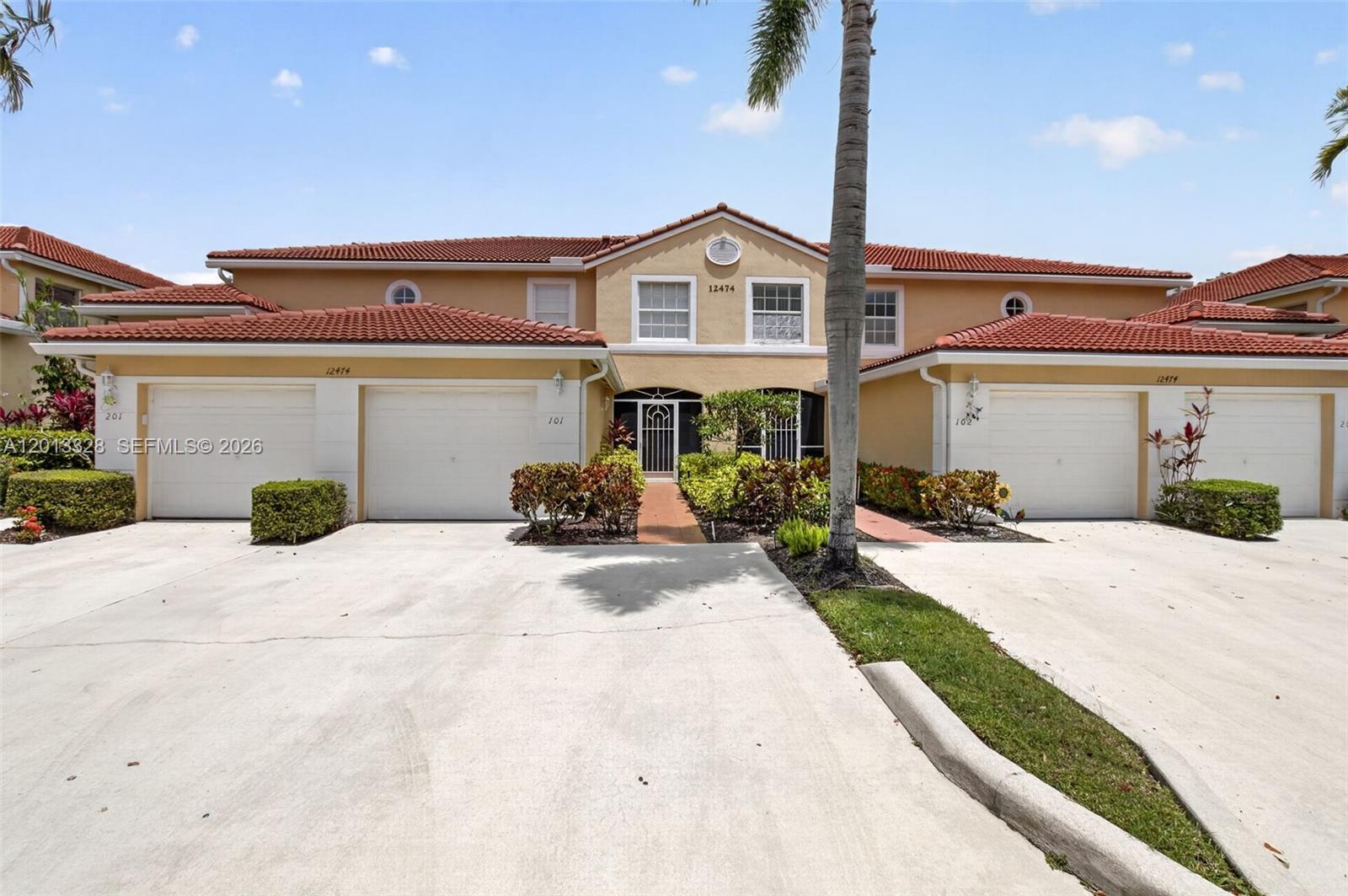 A two-story townhouse exterior features a beige stucco facade, red tile roof, and two garages — 12474 Crystal Pointe Dr # 101, Boynton Beach FL 33437, BOYNTON BEACH, FL