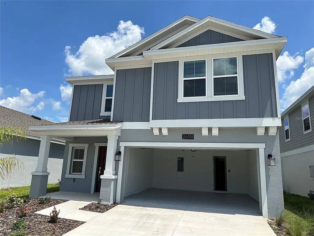 A two-story house with gray vertical siding, a white-trimmed garage, and a covered front porch — 26151 Feathergrass Circle, FL 34748, FL