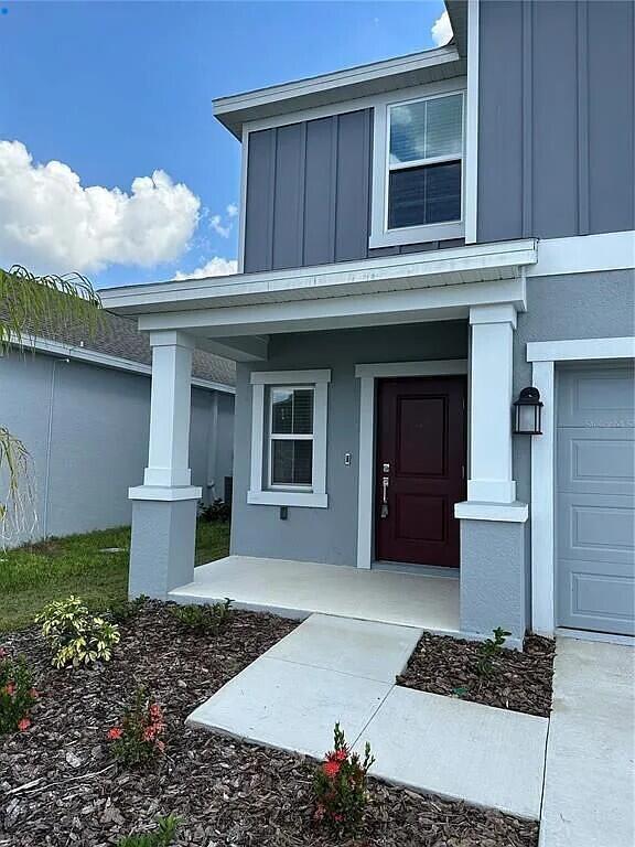 The exterior of a two-story gray house features a covered porch and a dark door — 26151 Feathergrass Circle, FL 34748, FL
