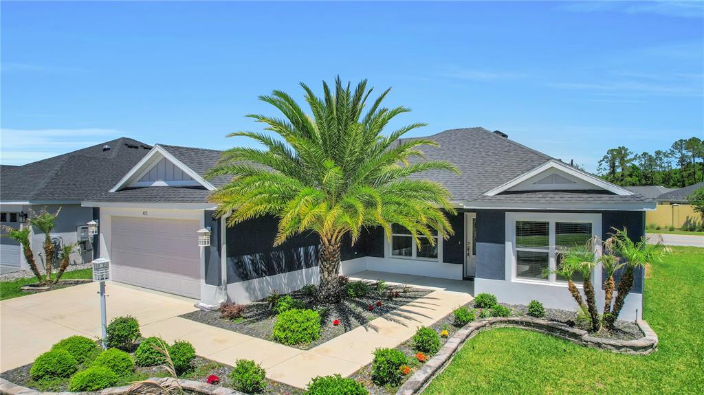 A single-story house with a dark blue exterior, a palm tree, and a concrete driveway — 4151 BALCHARAN TERRACE, THE VILLAGES, FL