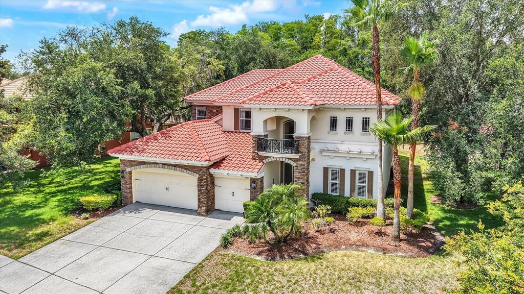 An aerial view of a two-story house with a red tile roof and stone accents — 9137 CREEDMOOR LANE, NEW PORT RICHEY, FL