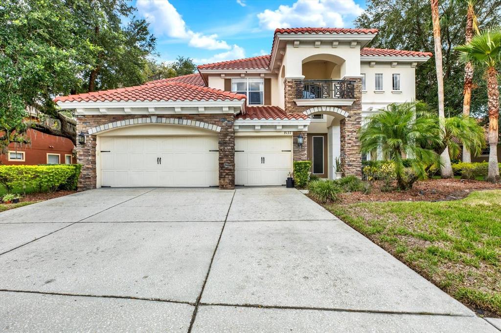 A two-story Mediterranean-style house features a tile roof, stone facade, and a three-car garage — 9137 CREEDMOOR LANE, NEW PORT RICHEY, FL