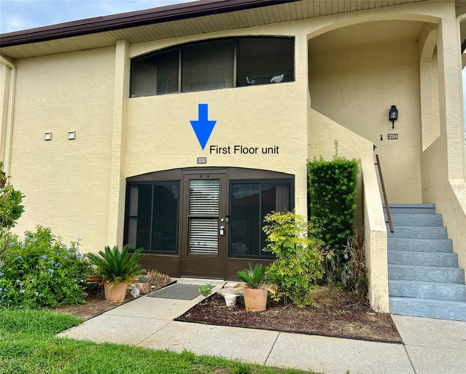 A beige two-story building exterior features a ground-level unit with a screened-in patio entrance — 2352 FOREST DRIVE UNIT 2352, INVERNESS, FL
