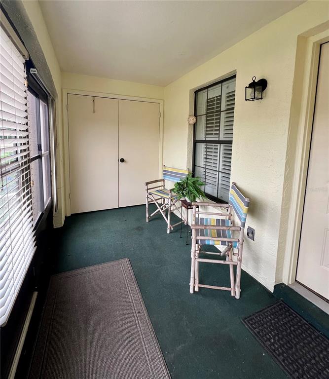 A covered porch features green carpeting, two folding chairs, a window, and a storage closet — 2352 FOREST DRIVE UNIT 2352, INVERNESS, FL