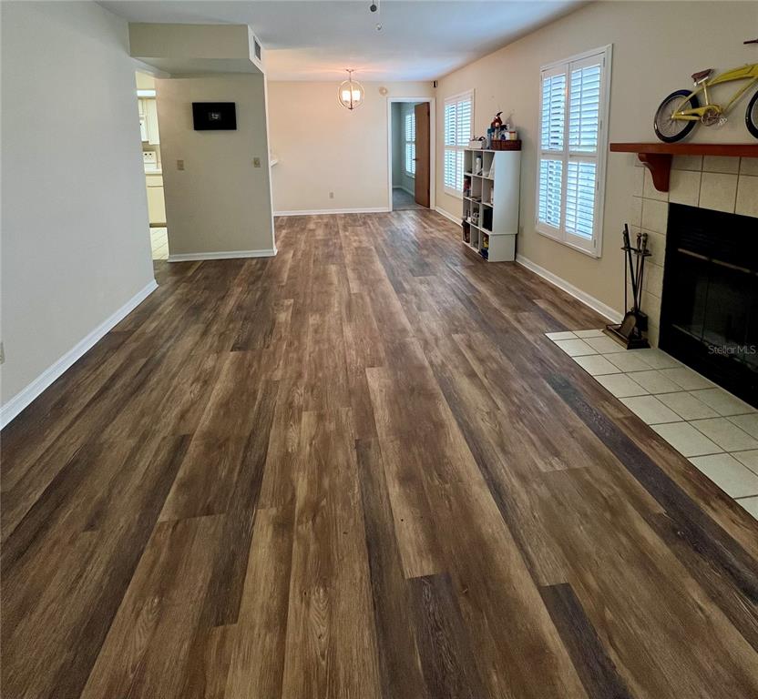 A living room features wood-look flooring, a fireplace with a mantle, and white plantation shutters — 2352 FOREST DRIVE UNIT 2352, INVERNESS, FL
