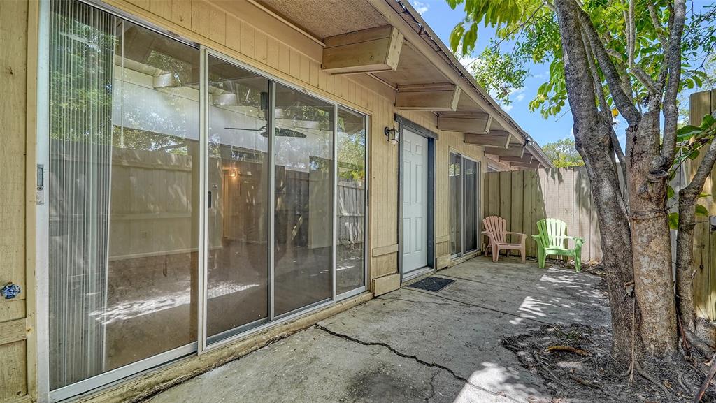 A concrete patio features sliding glass doors, a white door, and two chairs near a tree — 500 N JEFFERSON AVENUE UNIT B-5, SARASOTA, FL