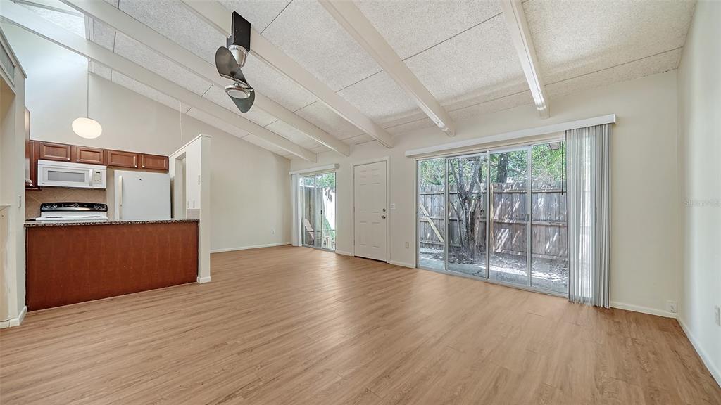 An open-concept living area features wood-look flooring, vaulted ceilings with exposed beams, and sliding glass doors — 500 N JEFFERSON AVENUE UNIT B-5, SARASOTA, FL
