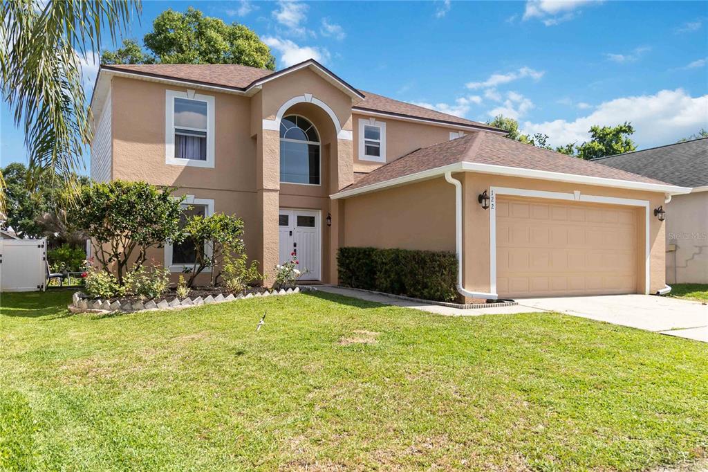A two-story tan house with a two-car garage and a front yard — 122 CARMEL BAY DRIVE, SANFORD, FL