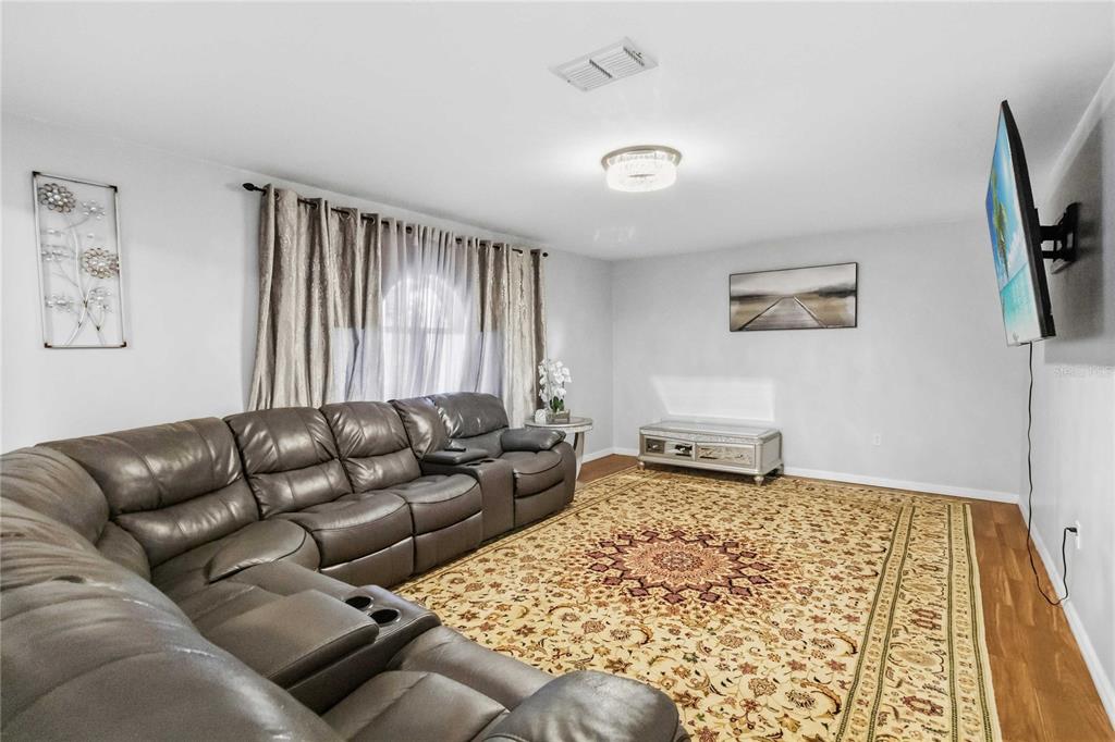A living room features a large gray sectional sofa, a patterned area rug, and a television — 122 CARMEL BAY DRIVE, SANFORD, FL