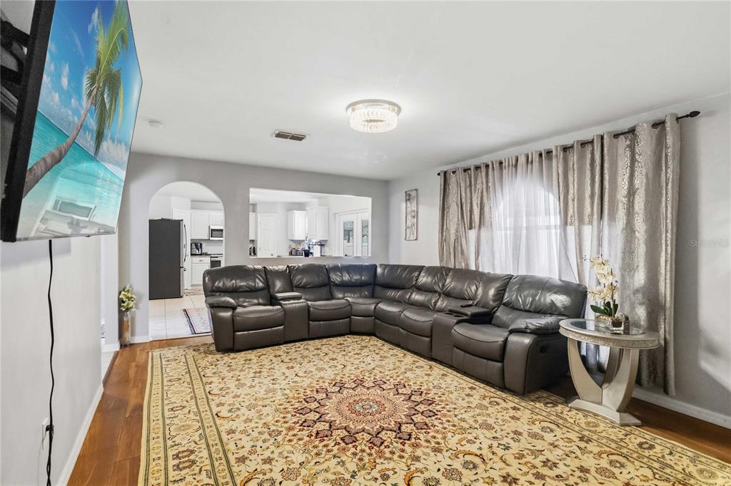 A living room features a large gray sectional sofa, a patterned rug, and a television — 122 CARMEL BAY DRIVE, SANFORD, FL