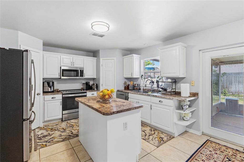 A kitchen features white cabinets, a central island with a brown countertop, and tile flooring — 122 CARMEL BAY DRIVE, SANFORD, FL