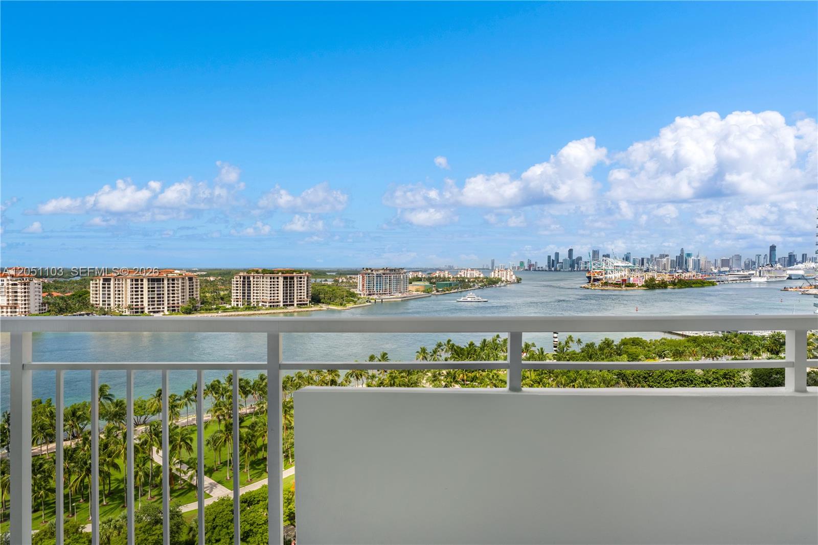 A balcony overlooks a waterway with palm trees and a distant city skyline — 400 S Pointe Dr # 1805, Miami Beach FL 33139, MIAMI BEACH, FL