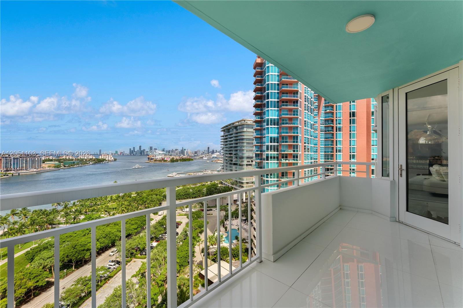 A balcony with white tile flooring overlooks a waterfront city skyline and park — 400 S Pointe Dr # 1805, Miami Beach FL 33139, MIAMI BEACH, FL