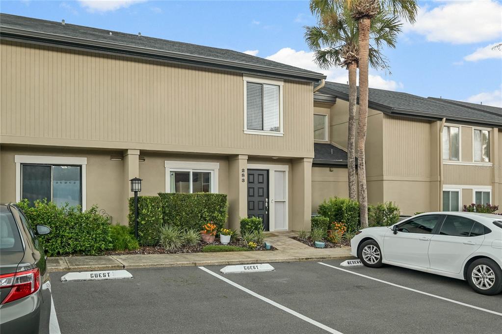 A two-story tan townhouse exterior with a front door, parking spaces, and a palm tree — 283 W LAKE FAITH DRIVE UNIT 146, MAITLAND, FL
