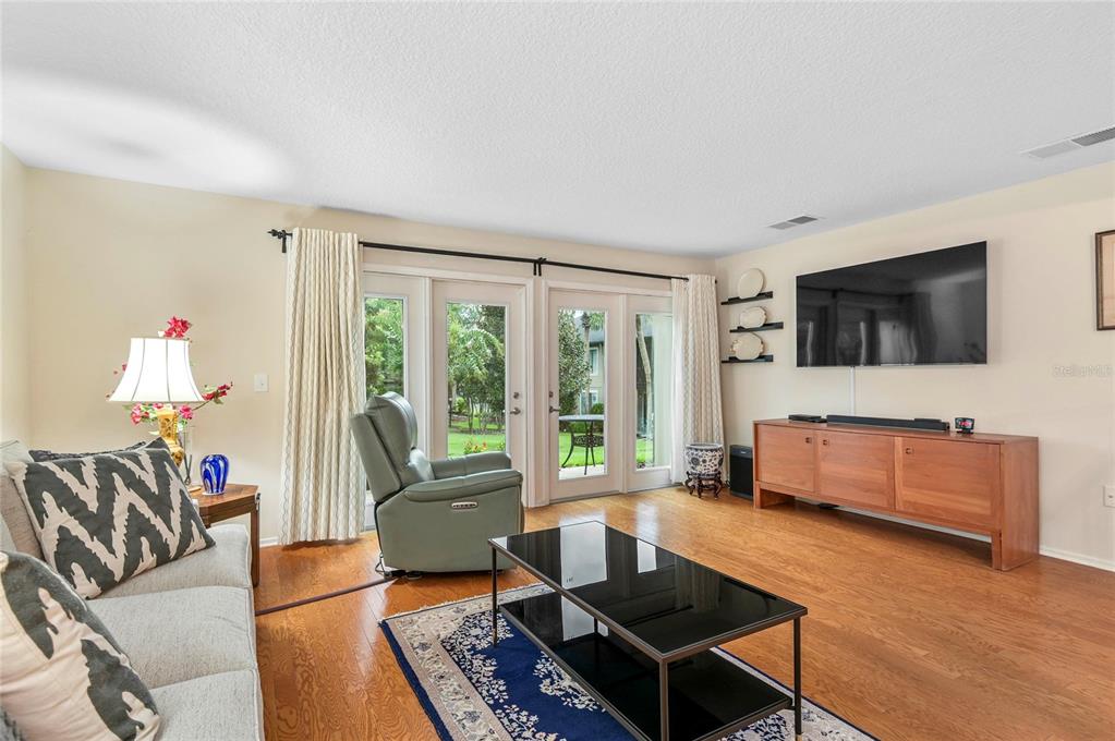 A living room features hardwood floors, a television, a glass coffee table, and glass doors — 283 W LAKE FAITH DRIVE UNIT 146, MAITLAND, FL