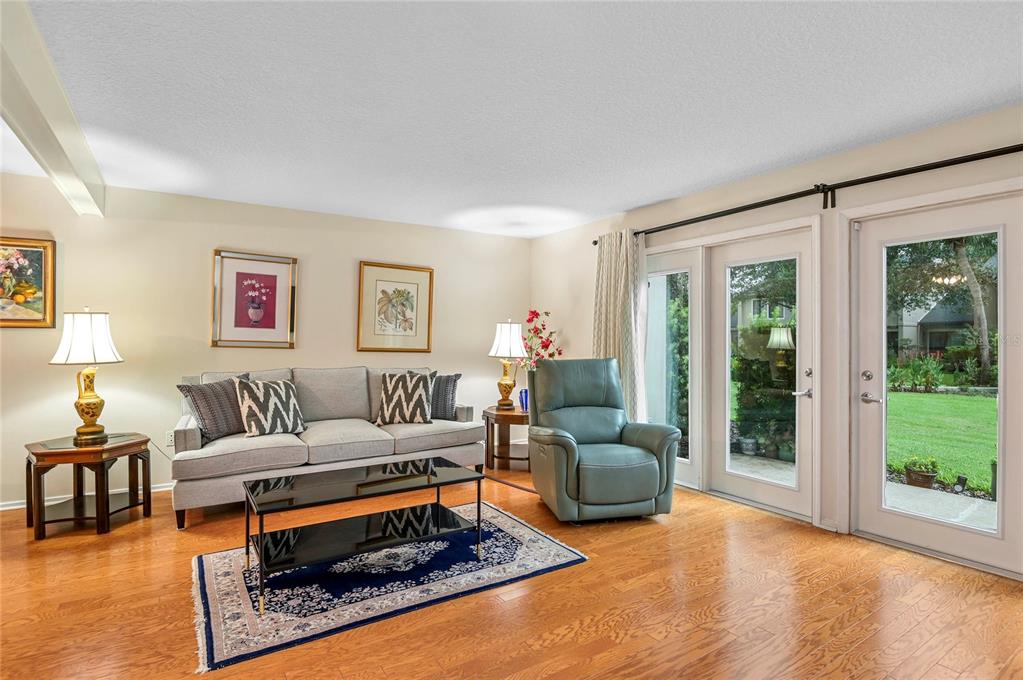 A living room with hardwood floors, a gray sofa, a blue recliner, and glass patio doors — 283 W LAKE FAITH DRIVE UNIT 146, MAITLAND, FL