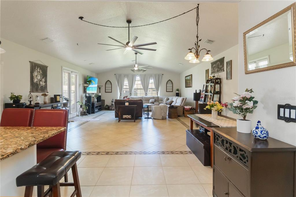 A spacious open-concept living room features tile flooring, a ceiling fan, and a dining area — 439 VIRGINIA AVENUE, ST CLOUD, FL