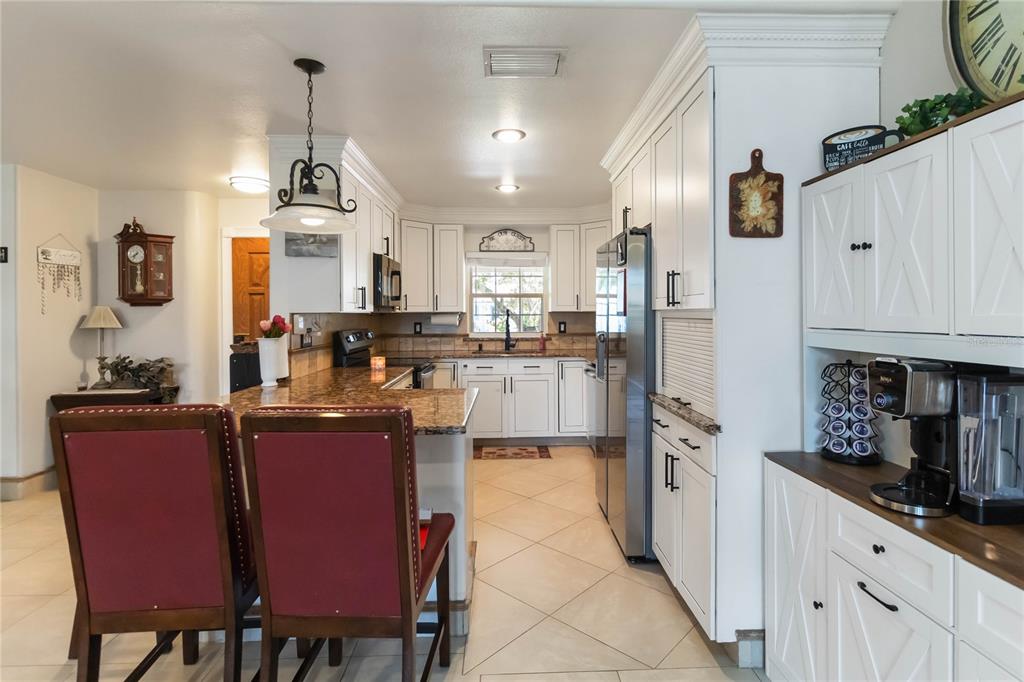 A kitchen features white cabinets, granite countertops, stainless steel appliances, and a breakfast bar — 439 VIRGINIA AVENUE, ST CLOUD, FL