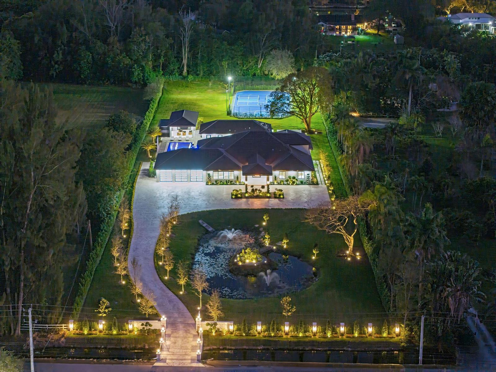 An aerial night view of a large house with a fountain, pool, and tennis court — 13110 Mustang Trail, Southwest Ranches FL 33330, SOUTHWEST RANCHES, FL