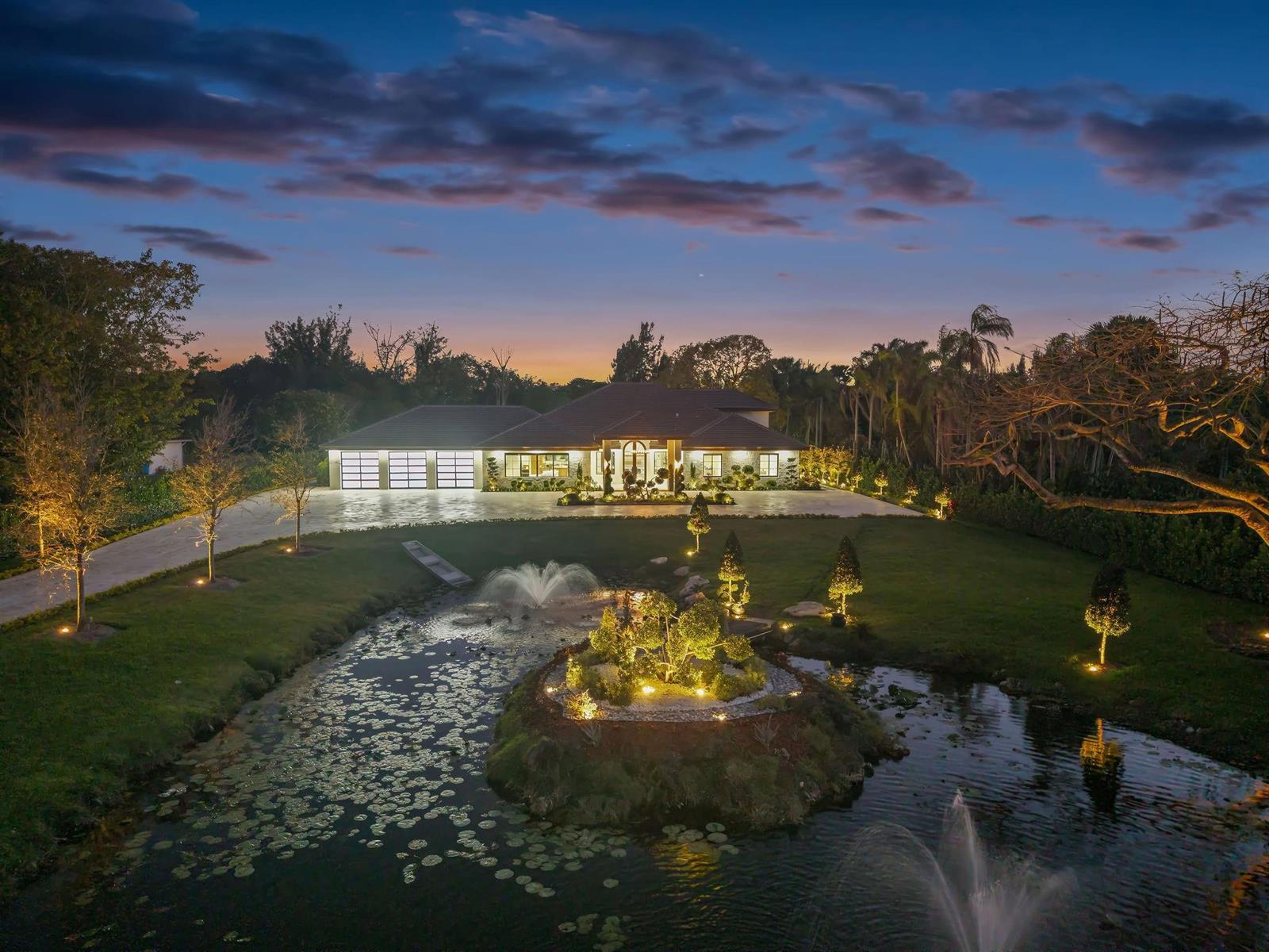 An aerial view of a house at dusk with a pond, fountain, and landscaped island — 13110 Mustang Trail, Southwest Ranches FL 33330, SOUTHWEST RANCHES, FL