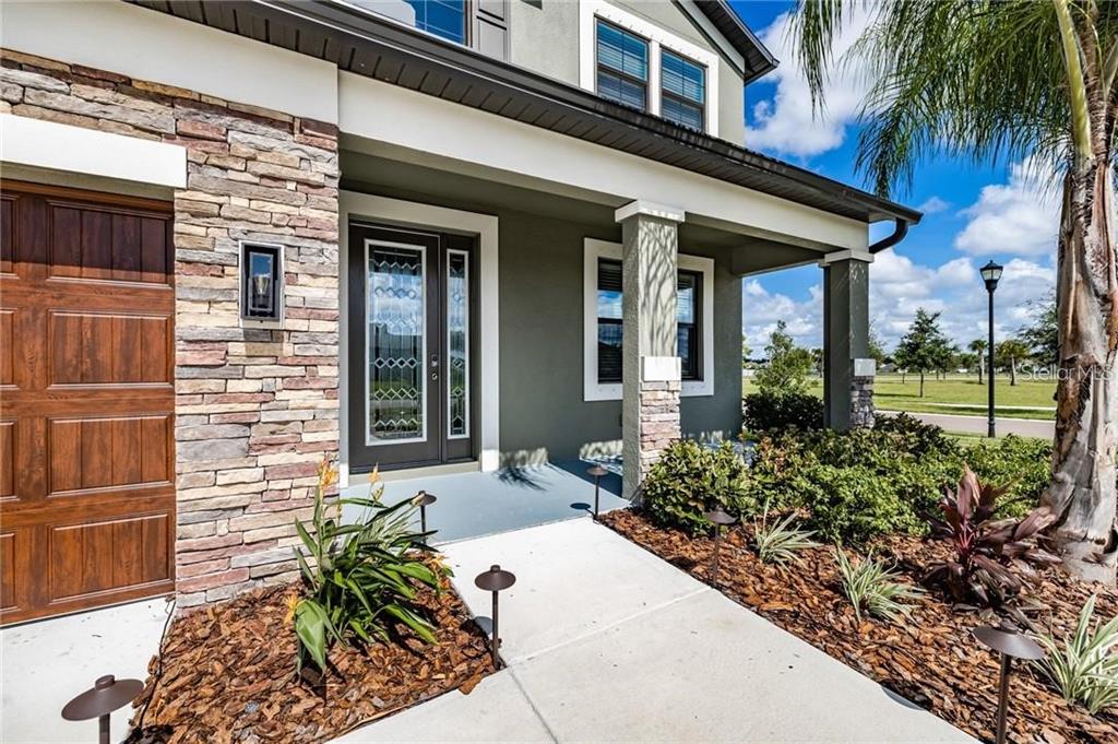 A front exterior view of a house with a stone facade, covered porch, and walkway — 11301 ALACHUA CREEK LANE, RIVERVIEW, FL