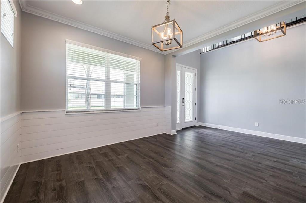 A dining room with white shiplap wainscoting, dark wood-look flooring, and a geometric pendant light — 11301 ALACHUA CREEK LANE, RIVERVIEW, FL