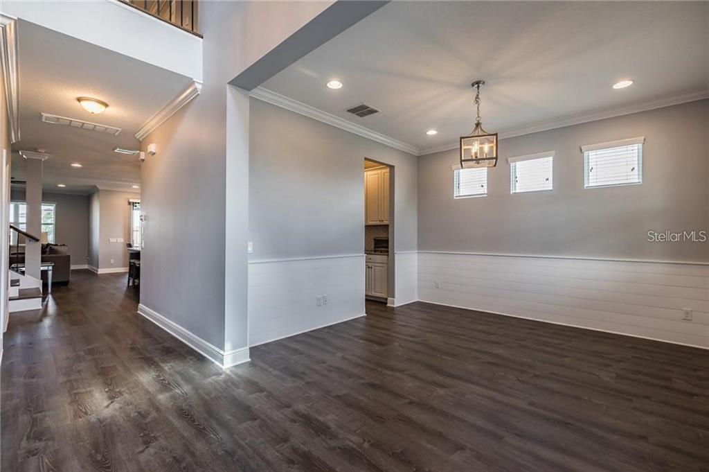 A dining room with white shiplap wainscoting, dark wood flooring, and a hanging lantern light — 11301 ALACHUA CREEK LANE, RIVERVIEW, FL