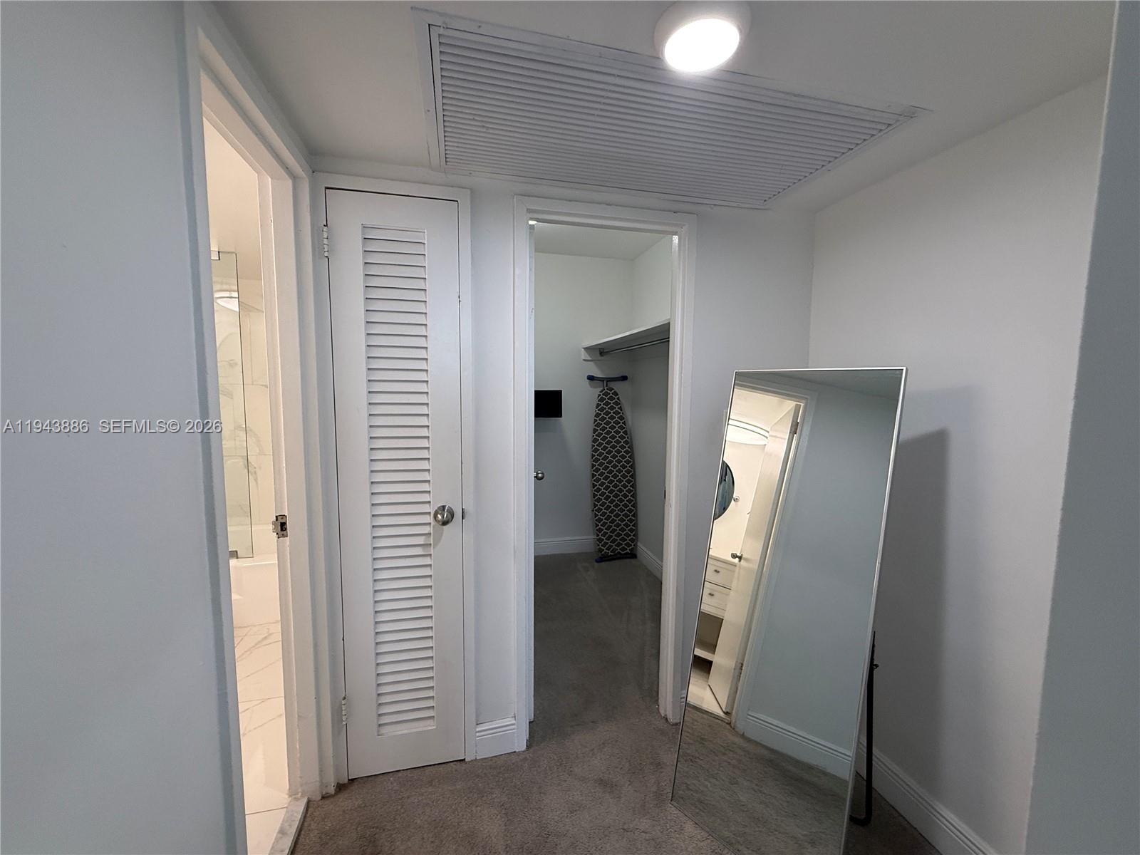 A hallway features a louvered door, a walk-in closet, and a full-length floor mirror — 5101 Collins Ave # 12T, Miami Beach FL 33140, MIAMI BEACH, FL