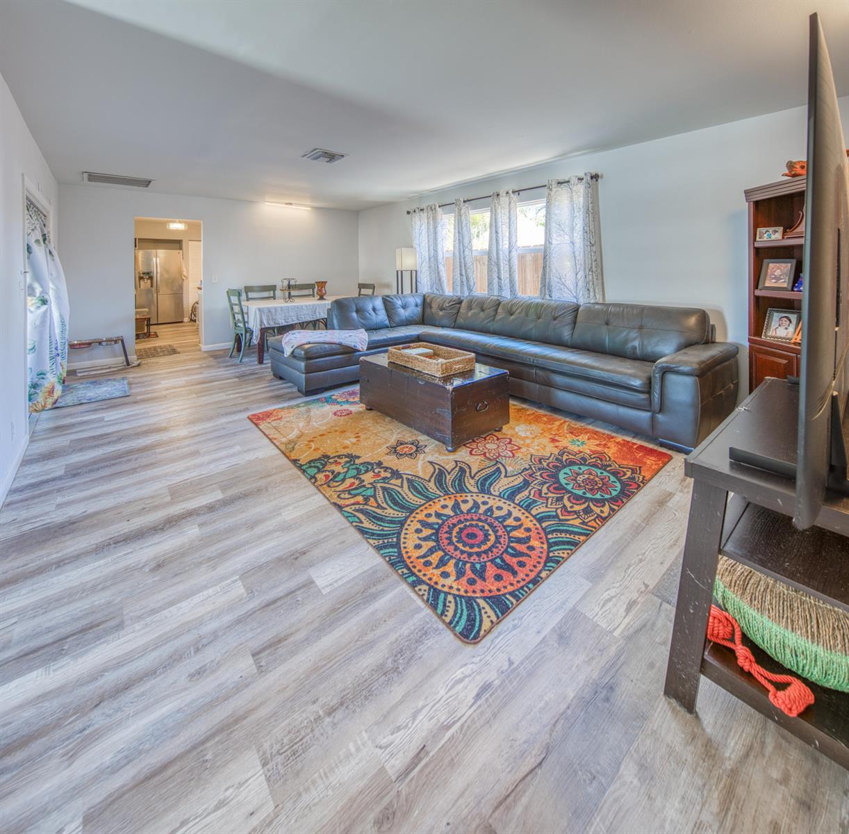 A living room features a large sectional sofa, a colorful area rug, and wood-look flooring — 1430 N N Street, FL 33460, FL