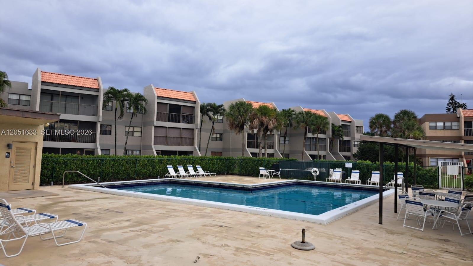 An outdoor swimming pool is surrounded by a concrete deck, lounge chairs, and apartment buildings — 230 Lakeview Dr # 310, Weston FL 33326, WESTON, FL