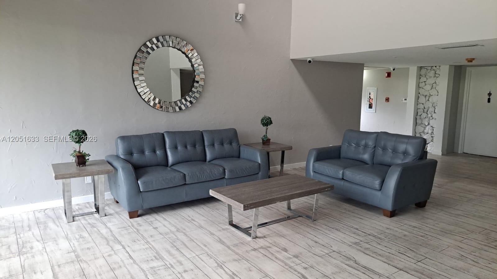 A living area features two blue leather sofas, a coffee table, and a circular mirror — 230 Lakeview Dr # 310, Weston FL 33326, WESTON, FL