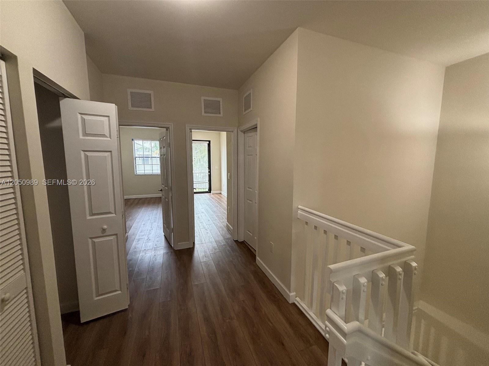 A hallway with wood-look flooring leads to two doorways and a white staircase railing — 10445 NW 61 LN # 10445, Doral FL 33178, DORAL, FL