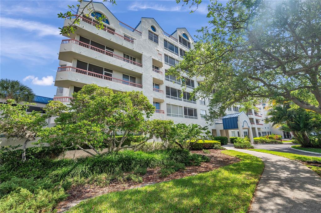 A multi-story residential building with balconies and arched windows surrounded by trees and landscaping — 2333 FEATHER SOUND DRIVE UNIT B307, CLEARWATER, FL