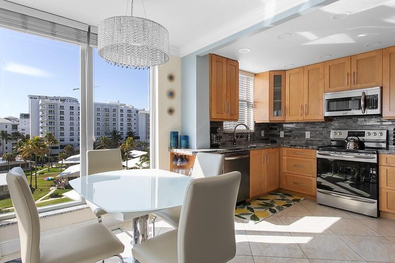A kitchen and dining area with light wood cabinets, stainless appliances, and large window views — 1010 S Ocean Boulevard # 602, Pompano Beach FL 33062, POMPANO BEACH, FL
