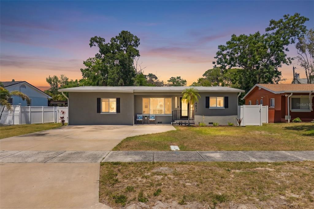 A single-story gray house with a concrete driveway and a white fence at sunset — 4832 5TH STREET S, ST PETERSBURG, FL