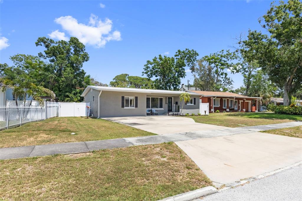 A single-story gray house with a concrete driveway and a white vinyl fence — 4832 5TH STREET S, ST PETERSBURG, FL