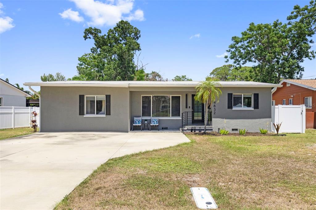 A single-story gray house with a concrete driveway, a front porch, and white fencing — 4832 5TH STREET S, ST PETERSBURG, FL