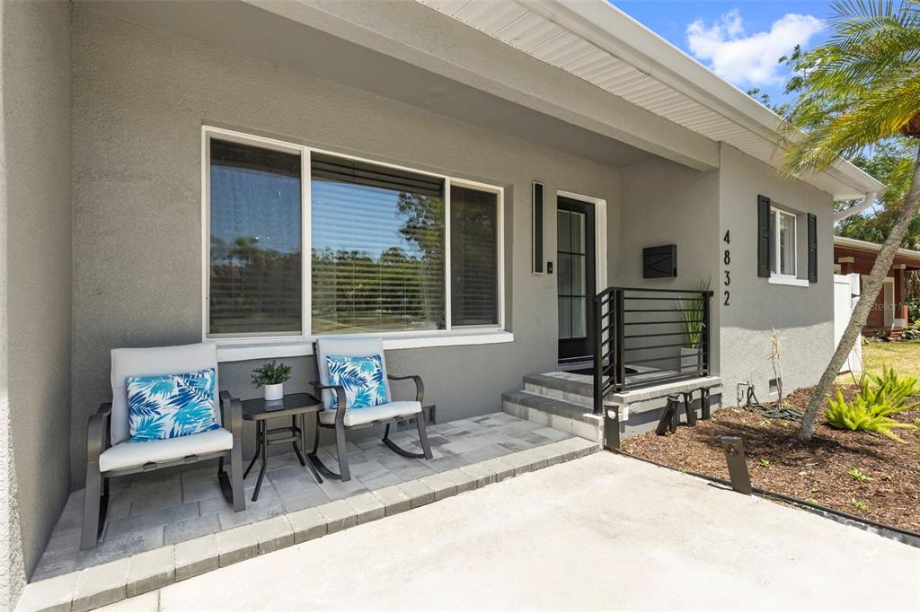 A gray house exterior features a front porch with two chairs, a table, and stairs — 4832 5TH STREET S, ST PETERSBURG, FL