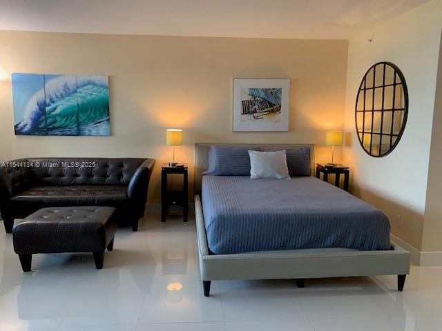 A bedroom features a dark leather sofa, a bed with a blue quilt, and tile flooring — 100 Lincoln Rd # 819, Miami Beach FL 33139, MIAMI BEACH, FL