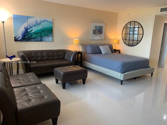 A studio apartment features a bed, a leather sofa, an ottoman, and white tile flooring — 100 Lincoln Rd # 819, Miami Beach FL 33139, MIAMI BEACH, FL