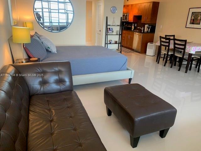 A studio apartment features a bed, a leather sofa with ottoman, and an open kitchen — 100 Lincoln Rd # 819, Miami Beach FL 33139, MIAMI BEACH, FL